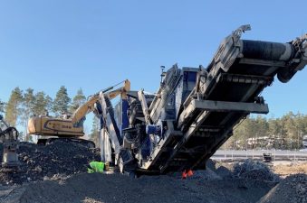 Iso työmaalaite betonijätekasan päällä.
