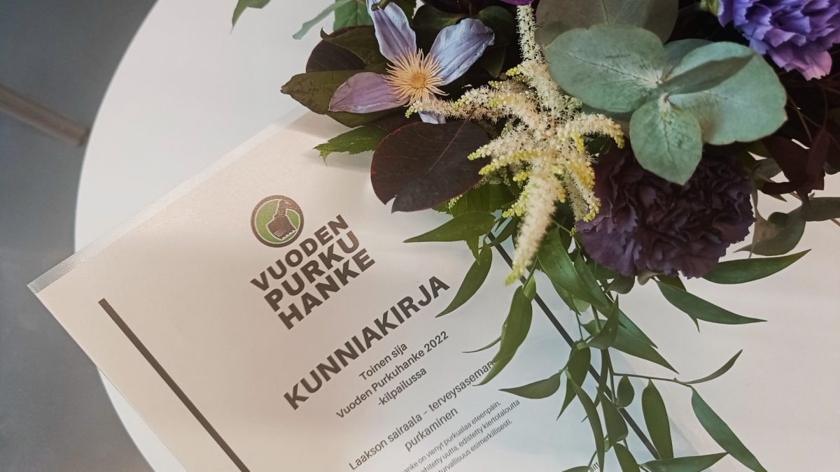 Kukkia maljakossa, pöydällä kunniakirja, jossa lukee: toinen sija Vuoden purkuhanke 2022 -kilpailussa, Laakson terveysaseman purkaminen.