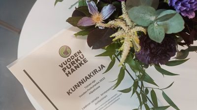 Kukkia maljakossa, pöydällä kunniakirja, jossa lukee: toinen sija Vuoden purkuhanke 2022 -kilpailussa, Laakson terveysaseman purkaminen.