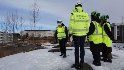 Neljä ihmistä seisoo lumessa taustallaan suuri rakennus.