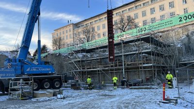Rakennusmiehiä työskentelee kuopan pohjalla talvisella työmaalla.