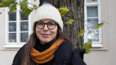 Nainen seisoo puunrungon edessä.