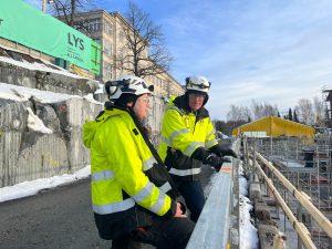 Kaksi henkilöä työmaavarusteissa työmaan laidalla.